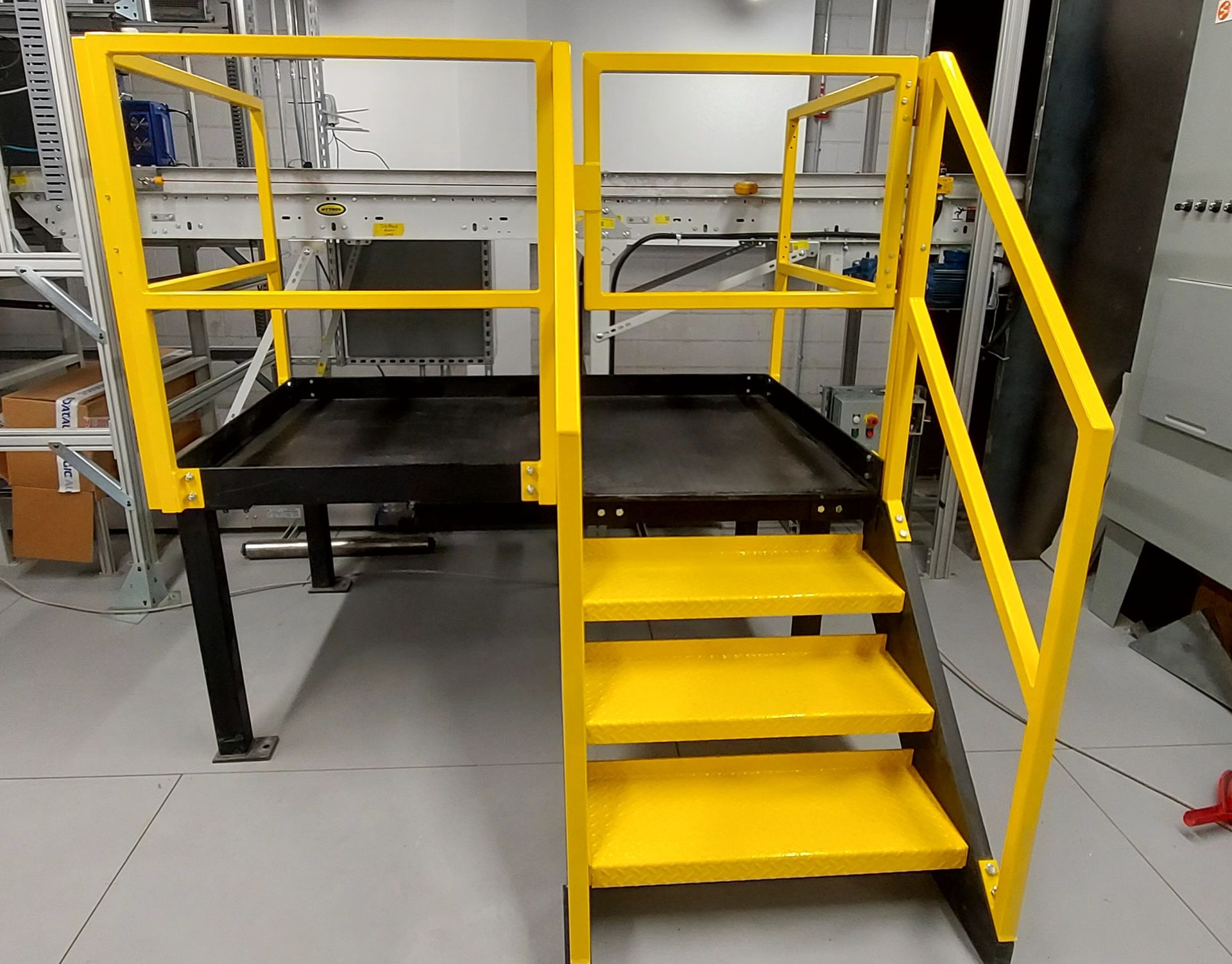A yellow metal platform with stairs and a railing in a room.