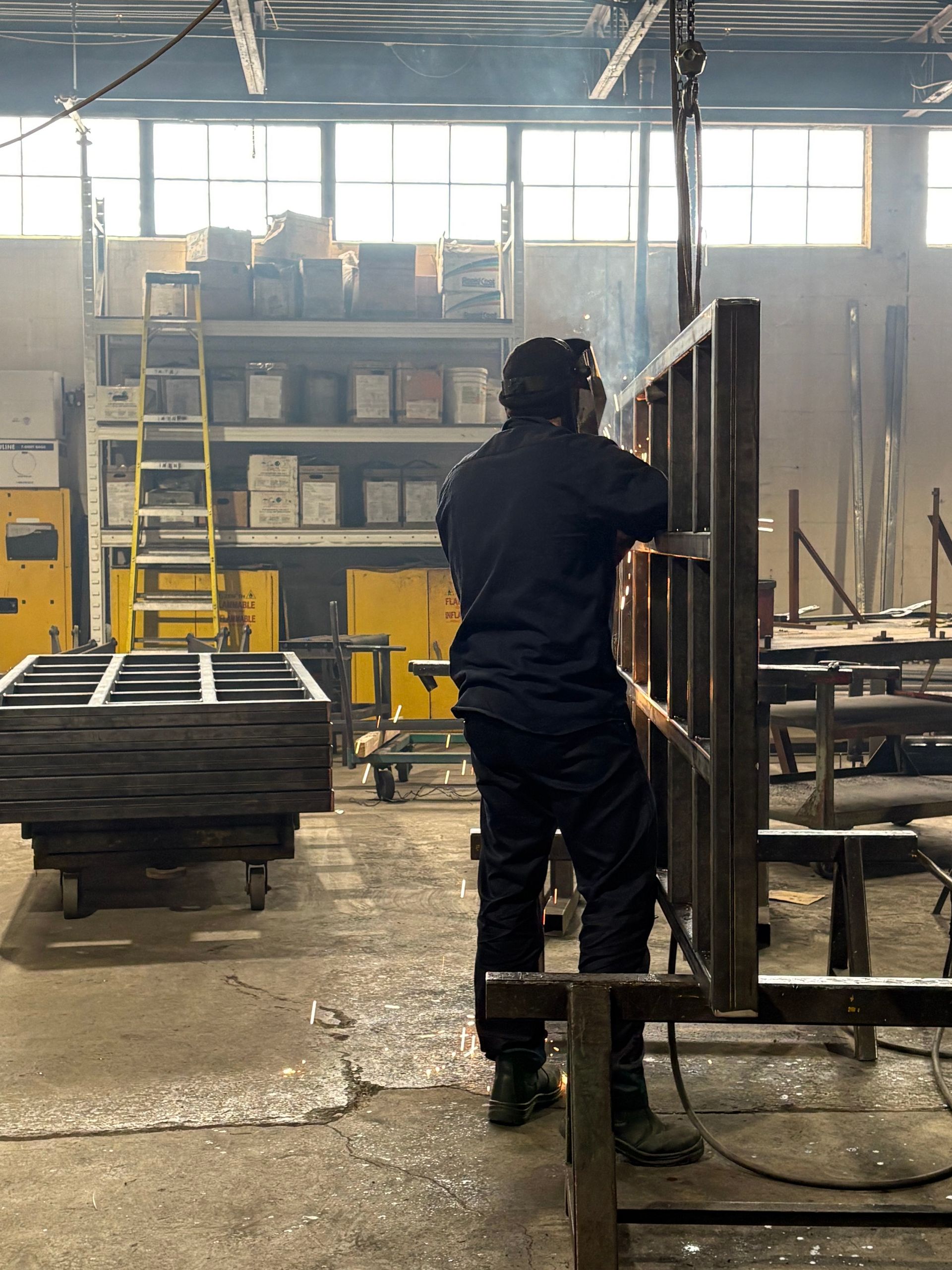 A man is welding a piece of metal in a factory