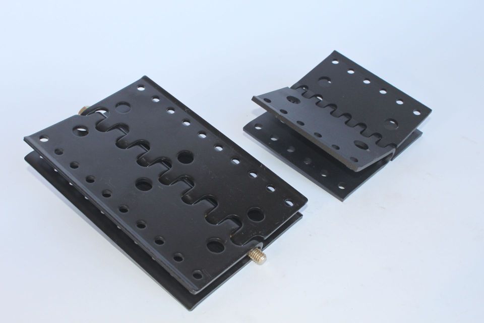 Two black pieces of metal with holes in them are stacked on top of each other
