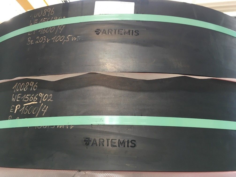 A snow grooming machine’s plow attachment, with its yellow blades and tracked wheels, resting on wooden planks.