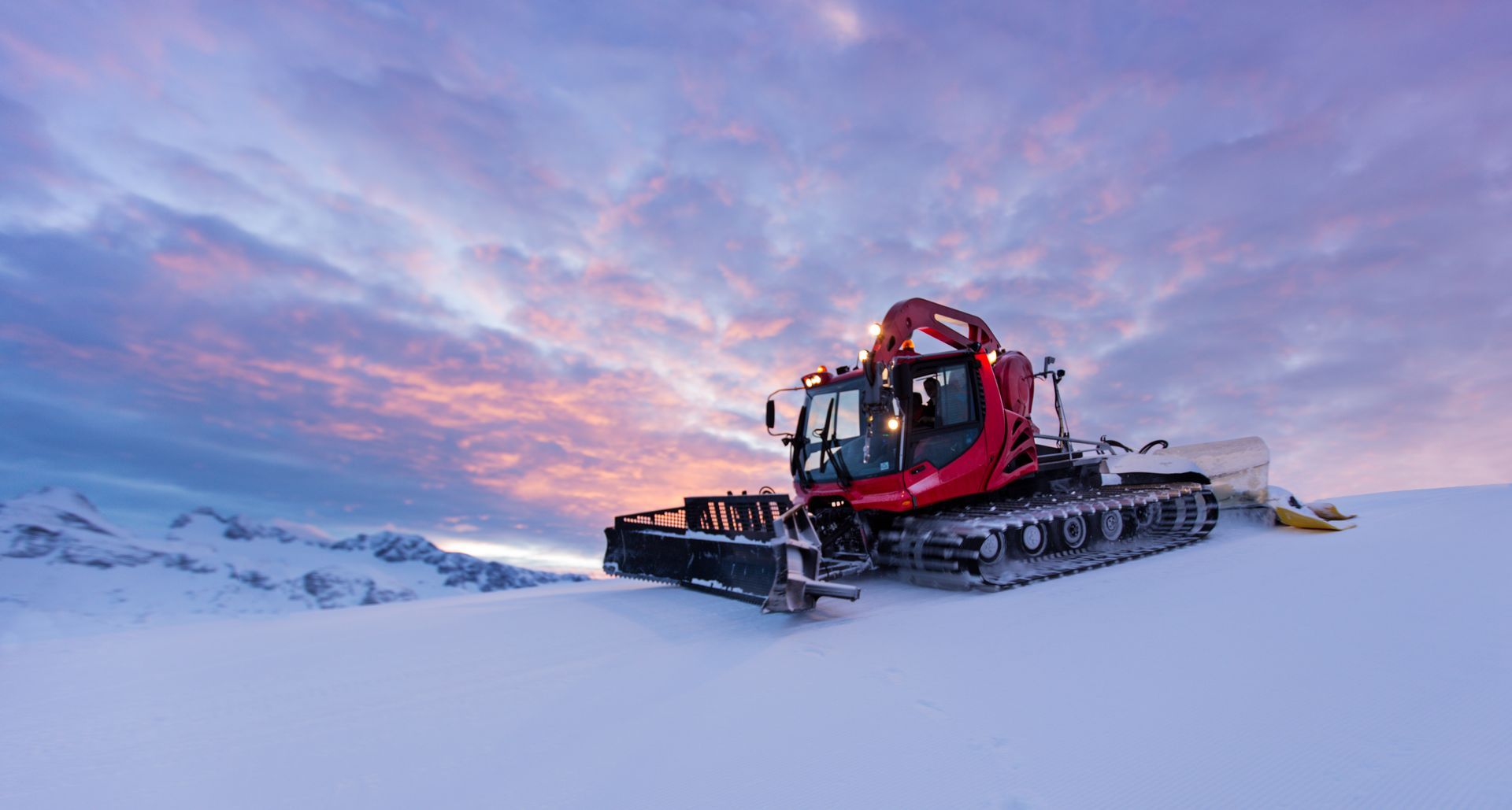 A snow plow is sitting on top of a snow covered mountain.
