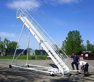 Two men are working on a ladder in a parking lot.