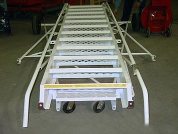 A metal ladder with wheels is sitting on a concrete floor.