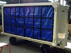 A white trailer with a blue tarp on it is sitting in a room.