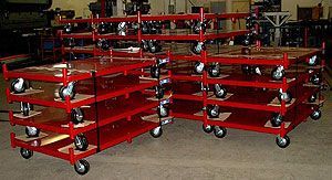 A bunch of red carts with wheels are stacked on top of each other.