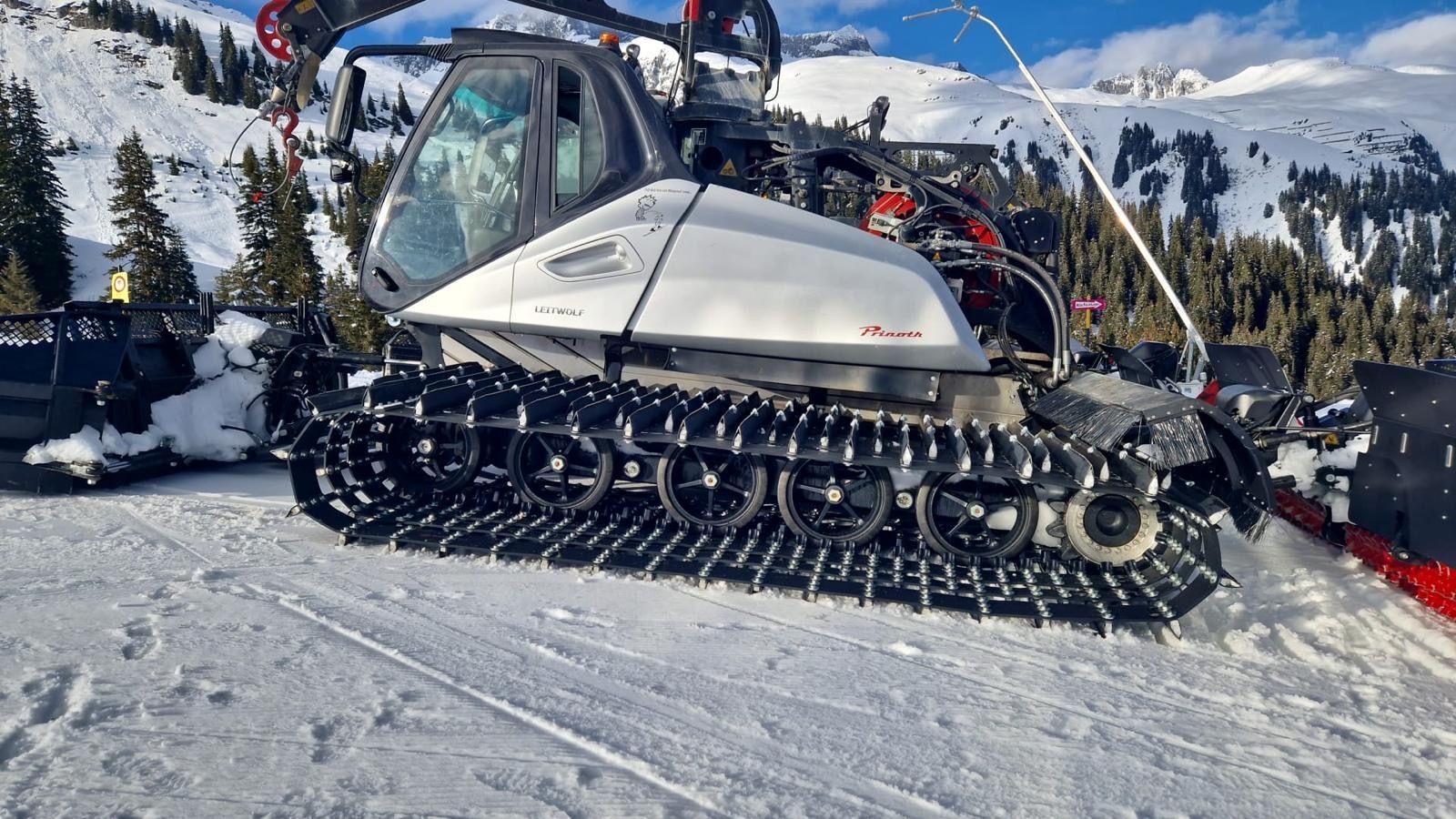 A snowmobile is parked in the snow on top of a snow covered mountain.