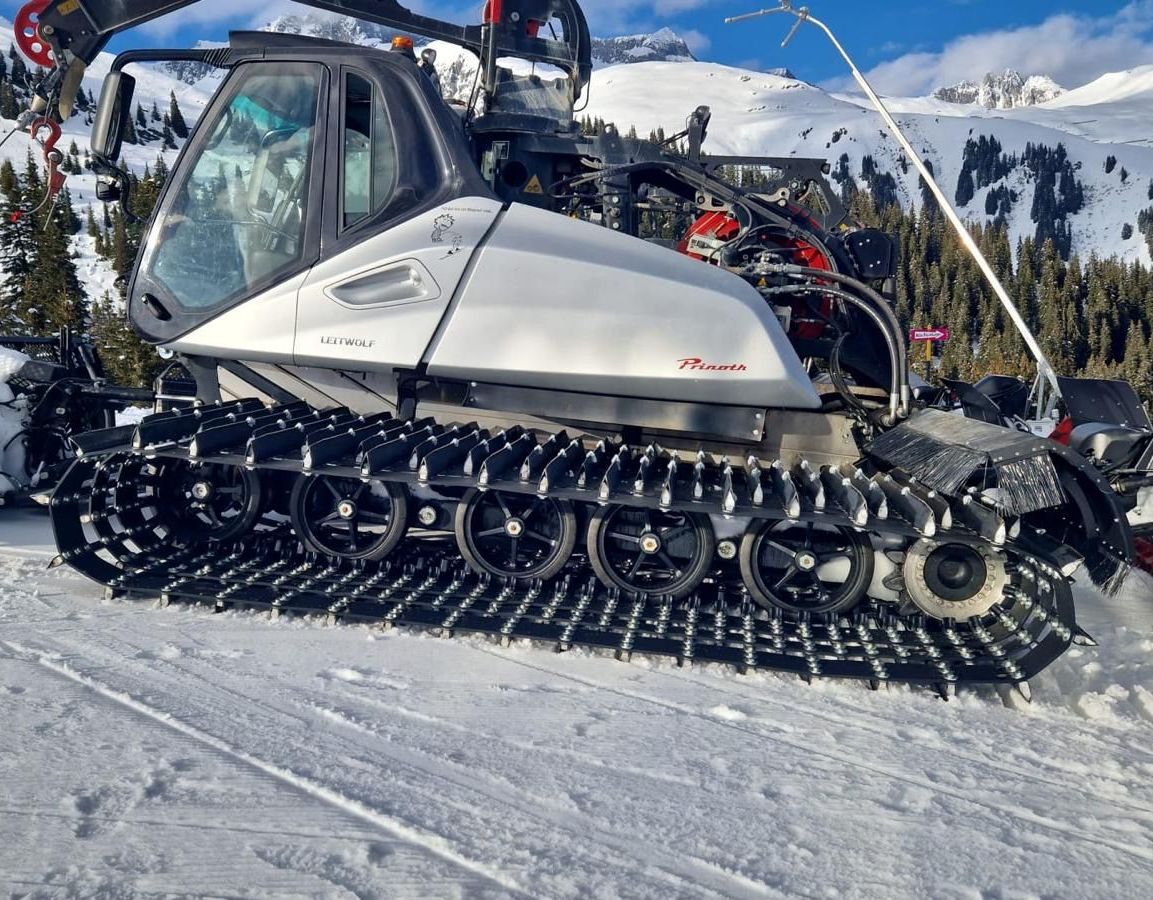 A snowmobile is parked in the snow on top of a snow covered mountain.