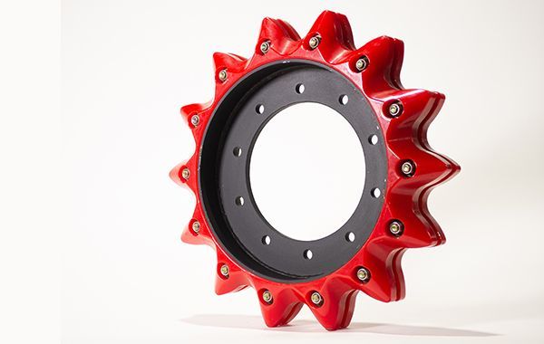 A red and black gear with holes in it is sitting on a white surface.