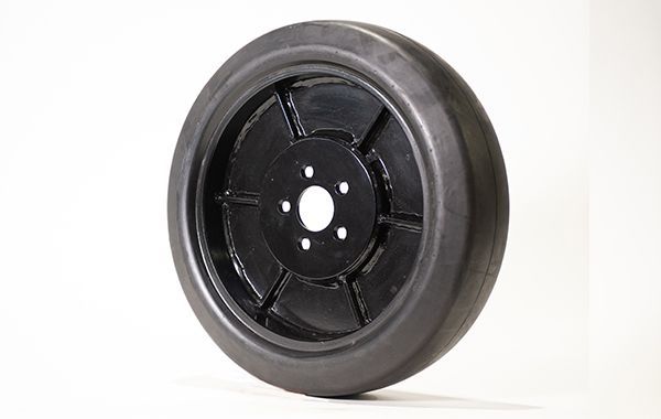 A close up of a black wheel on a white surface.