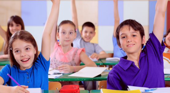 Classroom of students raising hands.