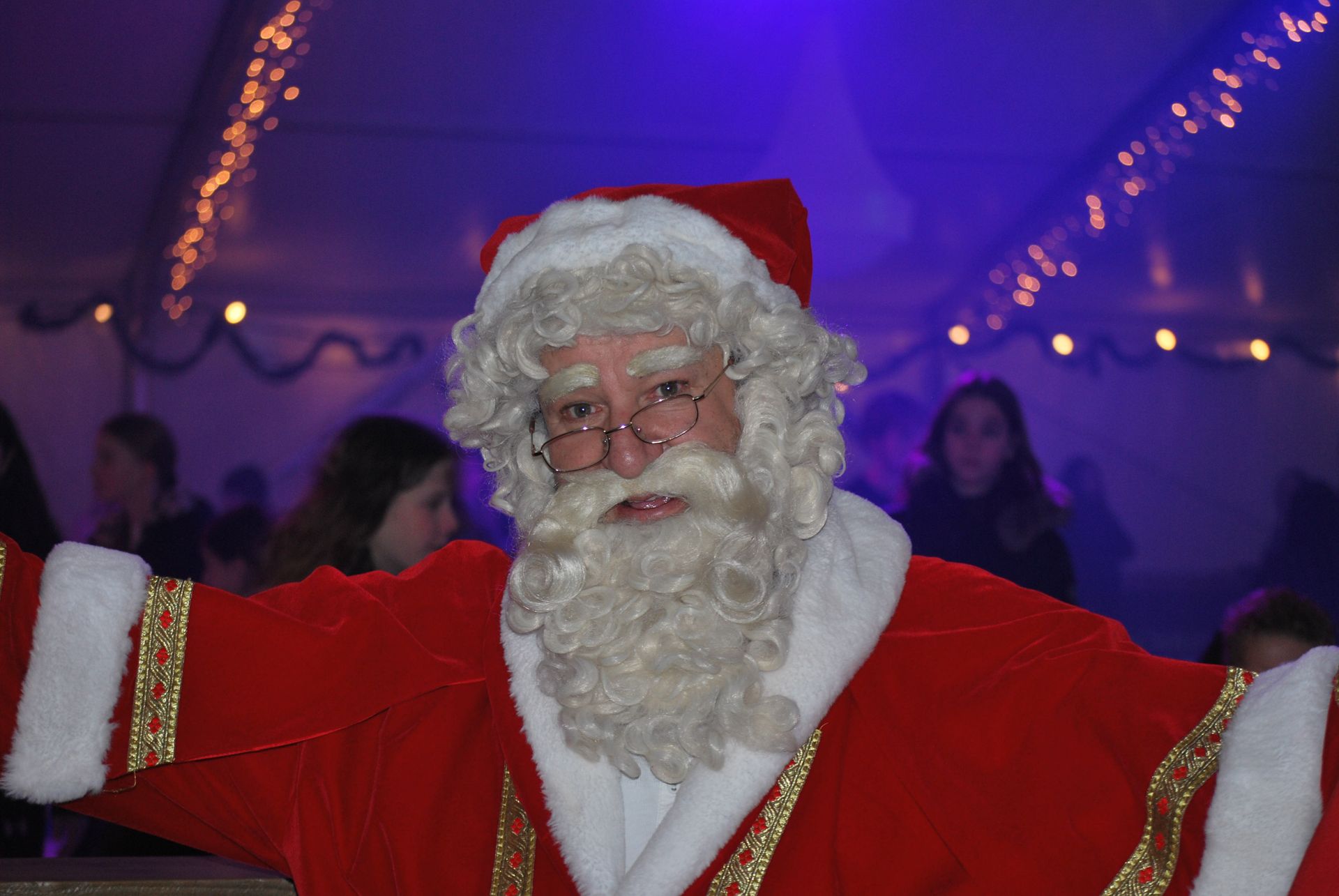 Een man verkleed als de kerstman met zijn armen uitgestrekt