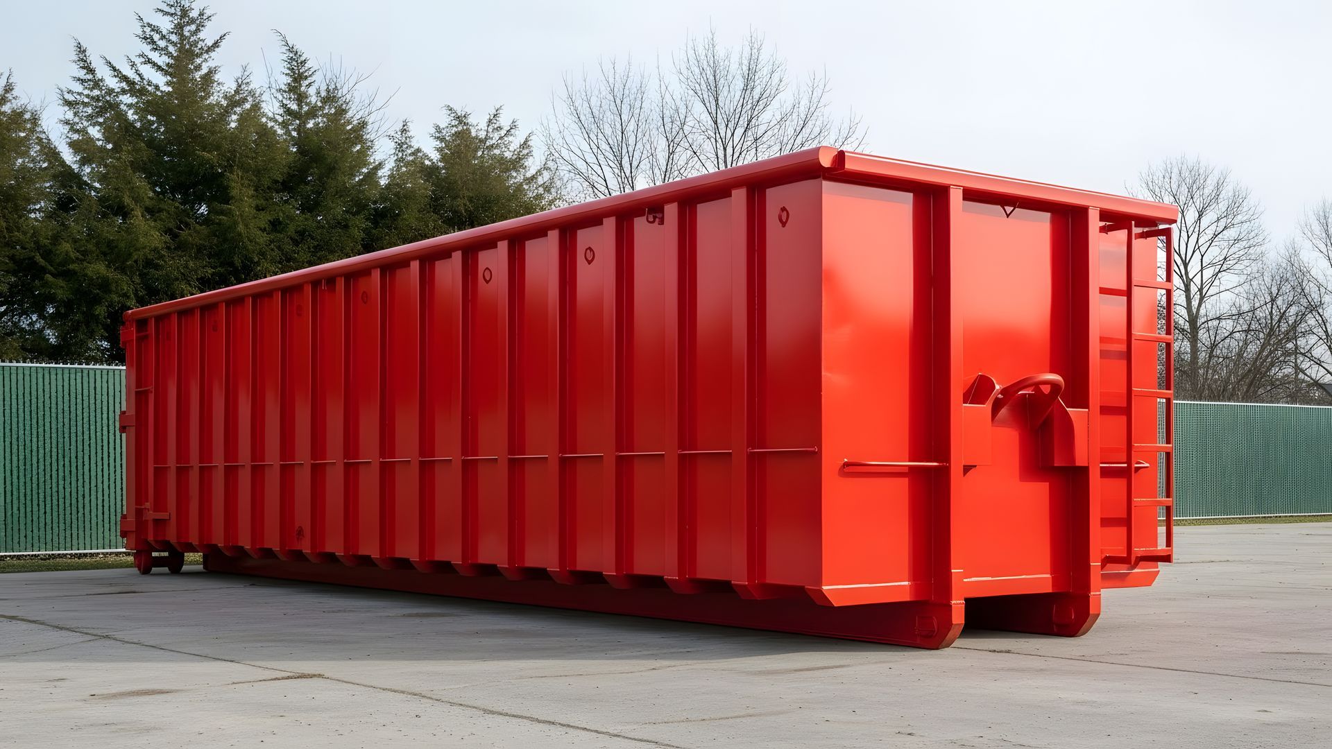 Large bright red roll-off dumpster container sitting on concrete slab. Large bright red roll-off dumpster container sitting on concrete slab.