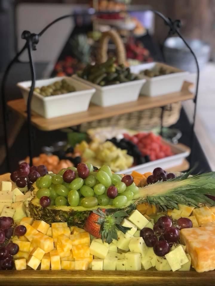 Fruit and cheese buffet with grapes, melon cubes, and trays of appetizers on a tiered stand