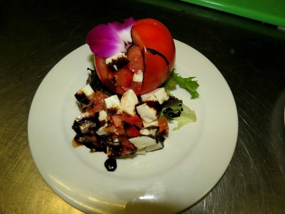 Plated gourmet dish with red tomato and white cheese garnish on a white plate