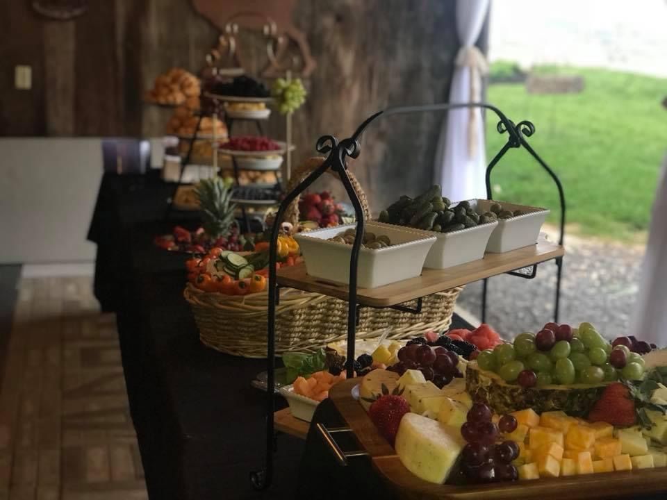 Fruit and cheese trays on tiered stands at a buffet table with grapes, melon, and strawberries.