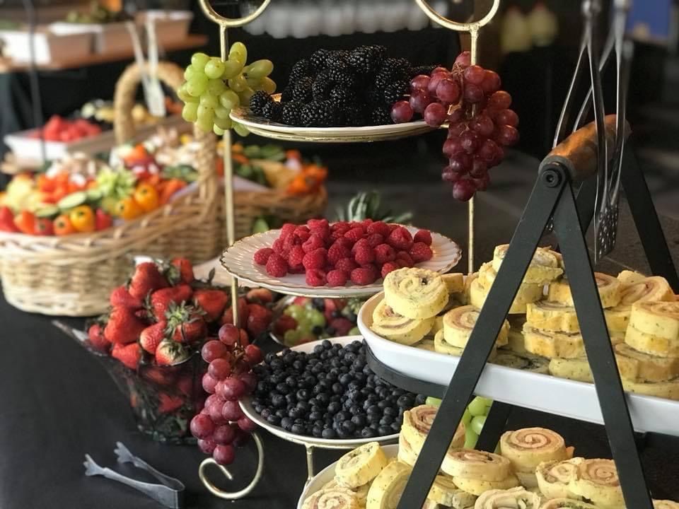 Tiered fruit display with grapes, strawberries, blackberries, and sliced apples on black trays
