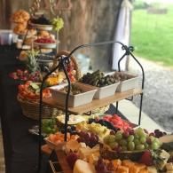 Tiered fruit platters on a buffet table with grapes, berries, and assorted sliced fruit outdoors