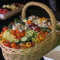 Woven basket filled with colorful sliced vegetables and garnishes on a table