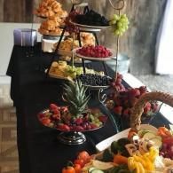 Assorted fruit and dessert platters arranged on tiered stands at a buffet table