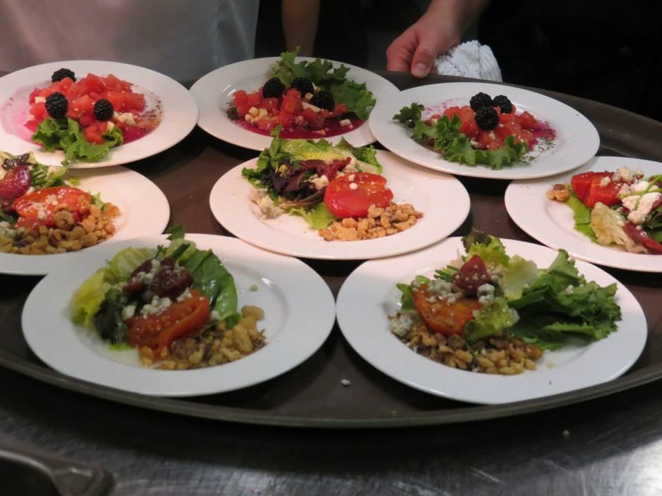 Platter of small white plates with colorful salads on a serving tray at a table