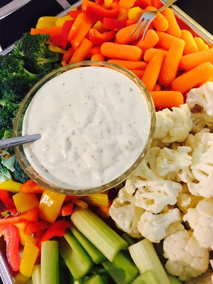 Fresh vegetable tray with dip, including carrots, celery, broccoli, bell peppers, and cauliflower