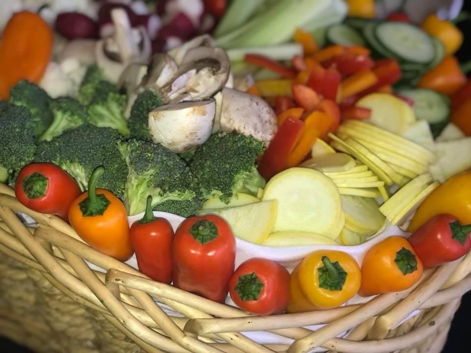 Basket of assorted fresh vegetables, including broccoli, peppers, onions, and squash.