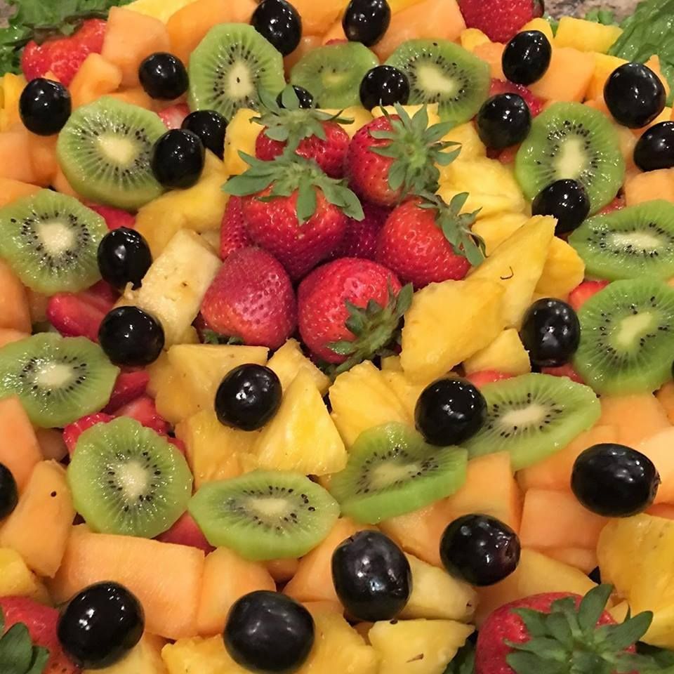 Assorted fruit platter with strawberries, kiwi, pineapple, melon, and black grapes