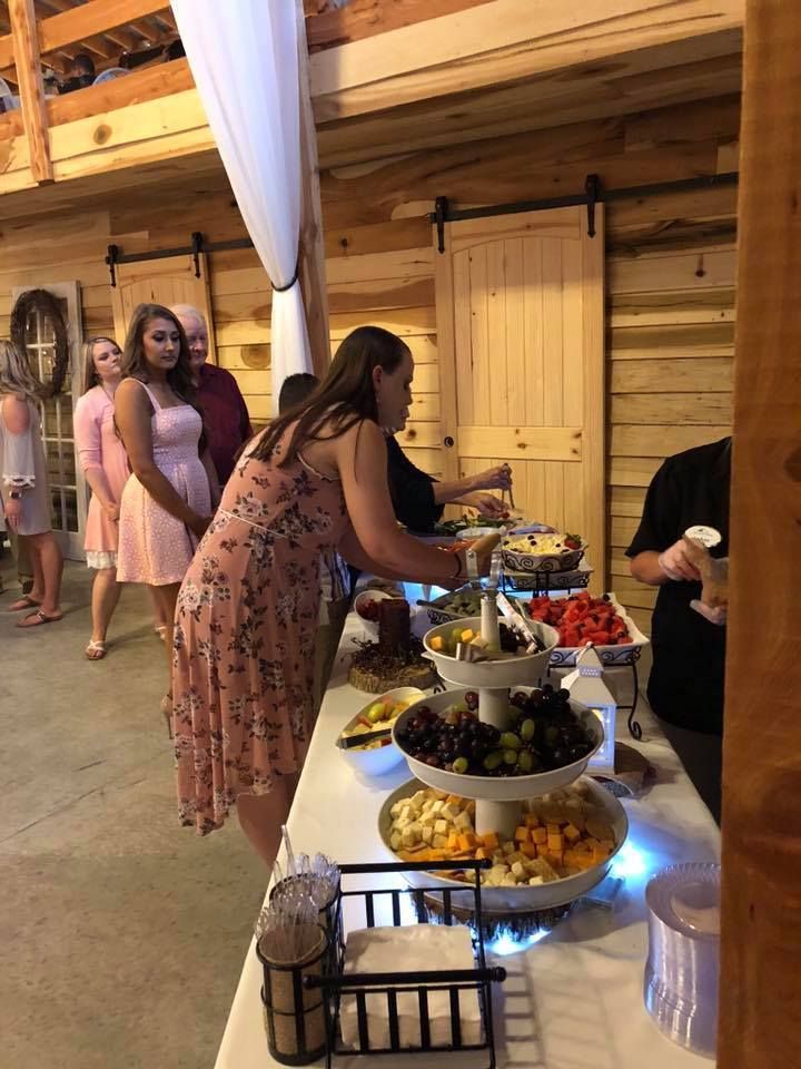 Guests serve themselves from a buffet table at an indoor event with warm wooden decor.
