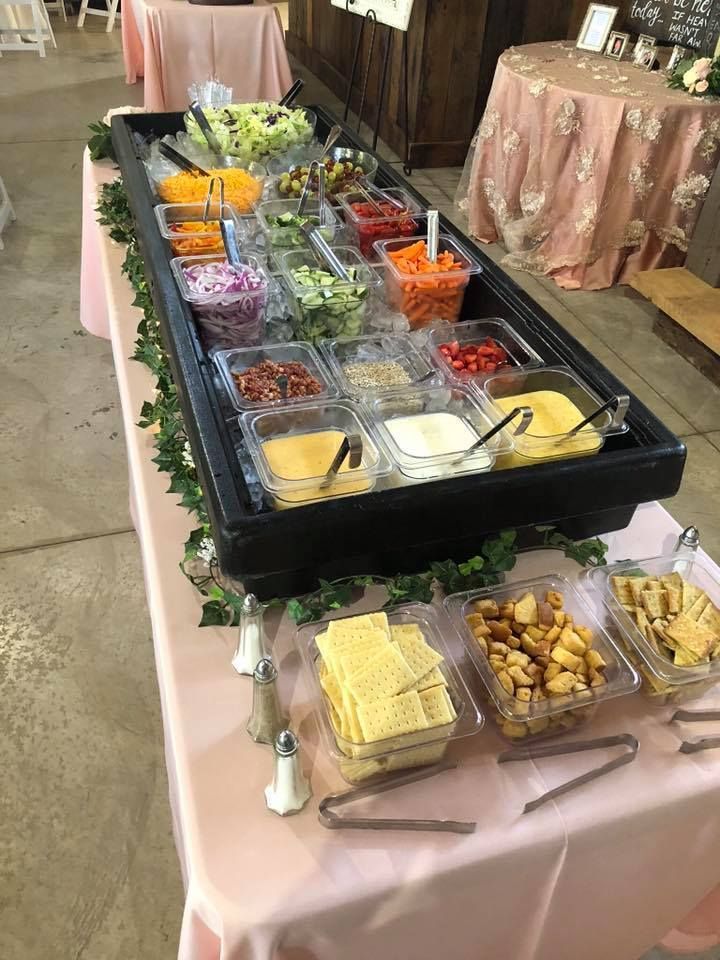 Buffet salad bar with assorted toppings and dressings on a decorated table