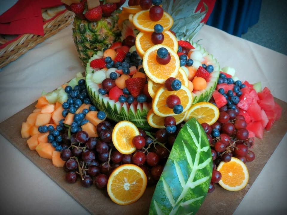 Fruit platter with oranges, grapes, berries, watermelon, and kiwi arranged decoratively on a table