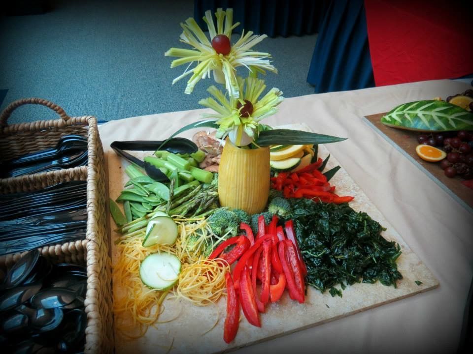 Decorative fruit and vegetable display on a table with a flower centerpiece
