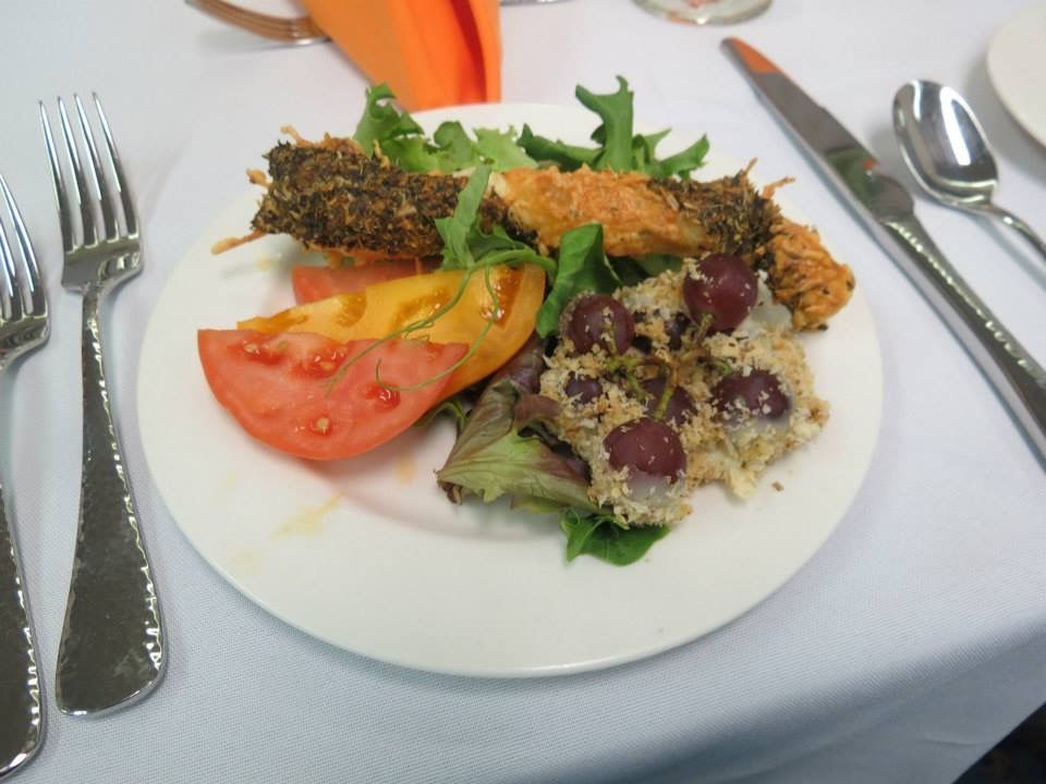Plated salad with tomatoes, greens, and grilled vegetables on a white tablecloth, with cutlery beside it