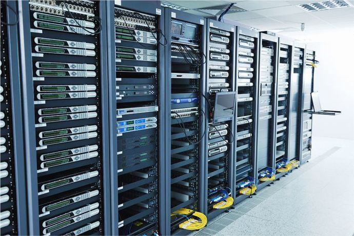 A row of grey server racks filled with networked hardware and visible cabling in a brightly lit data center.