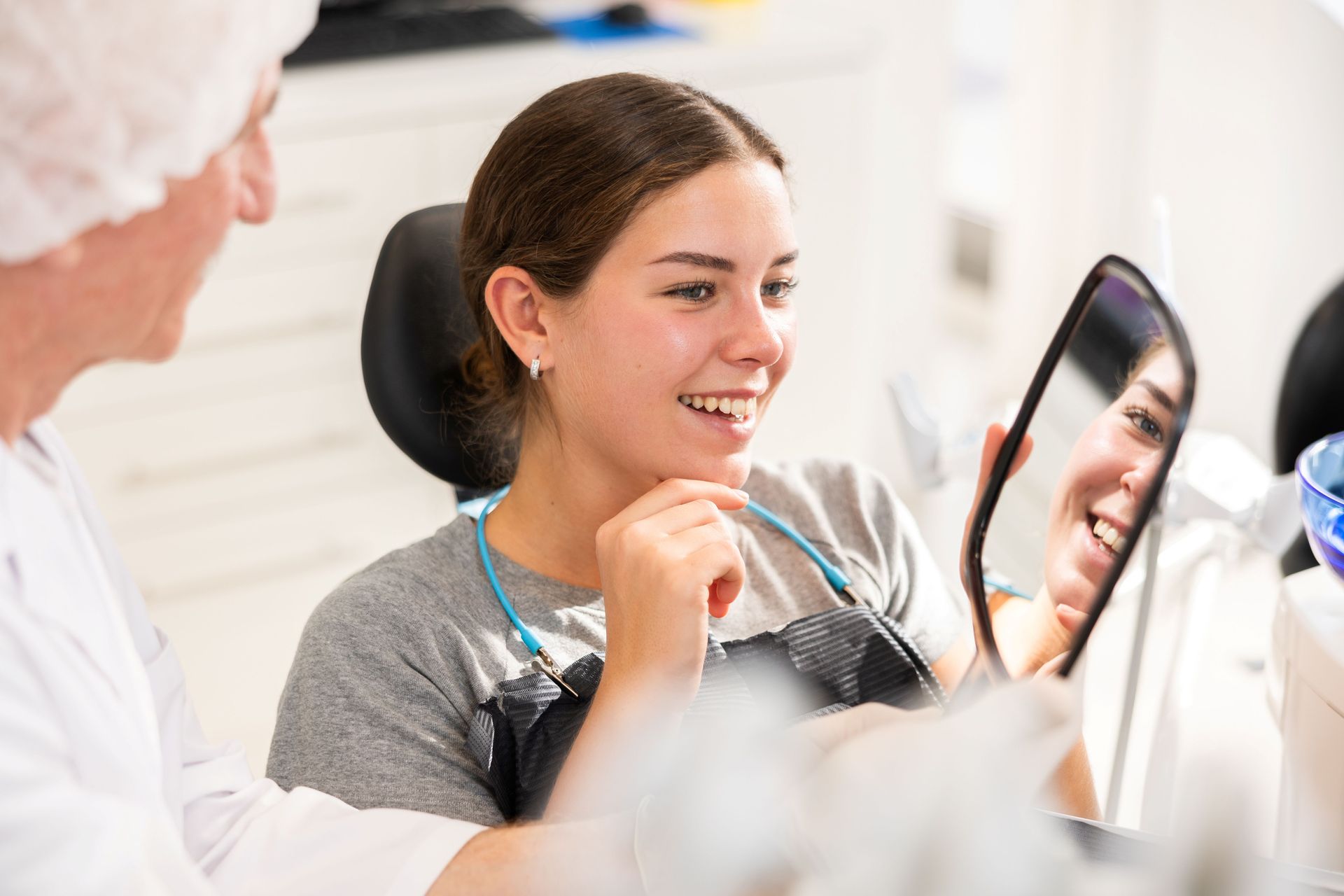 During an appointment, a dentist demonstrates to a patient the result of a cosmetic dental filling. During an appointment, a dentist demonstrates to a patient the result of a cosmetic dental filling.