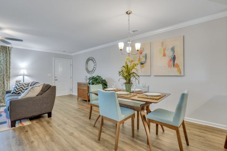 A living room with a dining table and chairs and a ceiling fan.