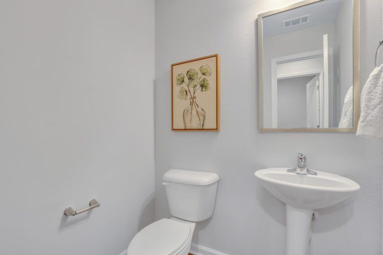 A bathroom with a toilet , sink and mirror.