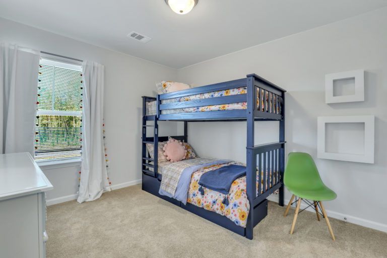A bedroom with a bunk bed and a green chair.