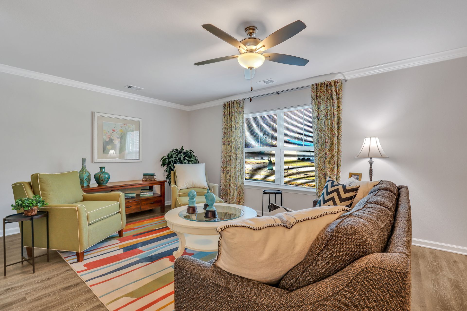 A living room with a couch , chairs , and a ceiling fan.