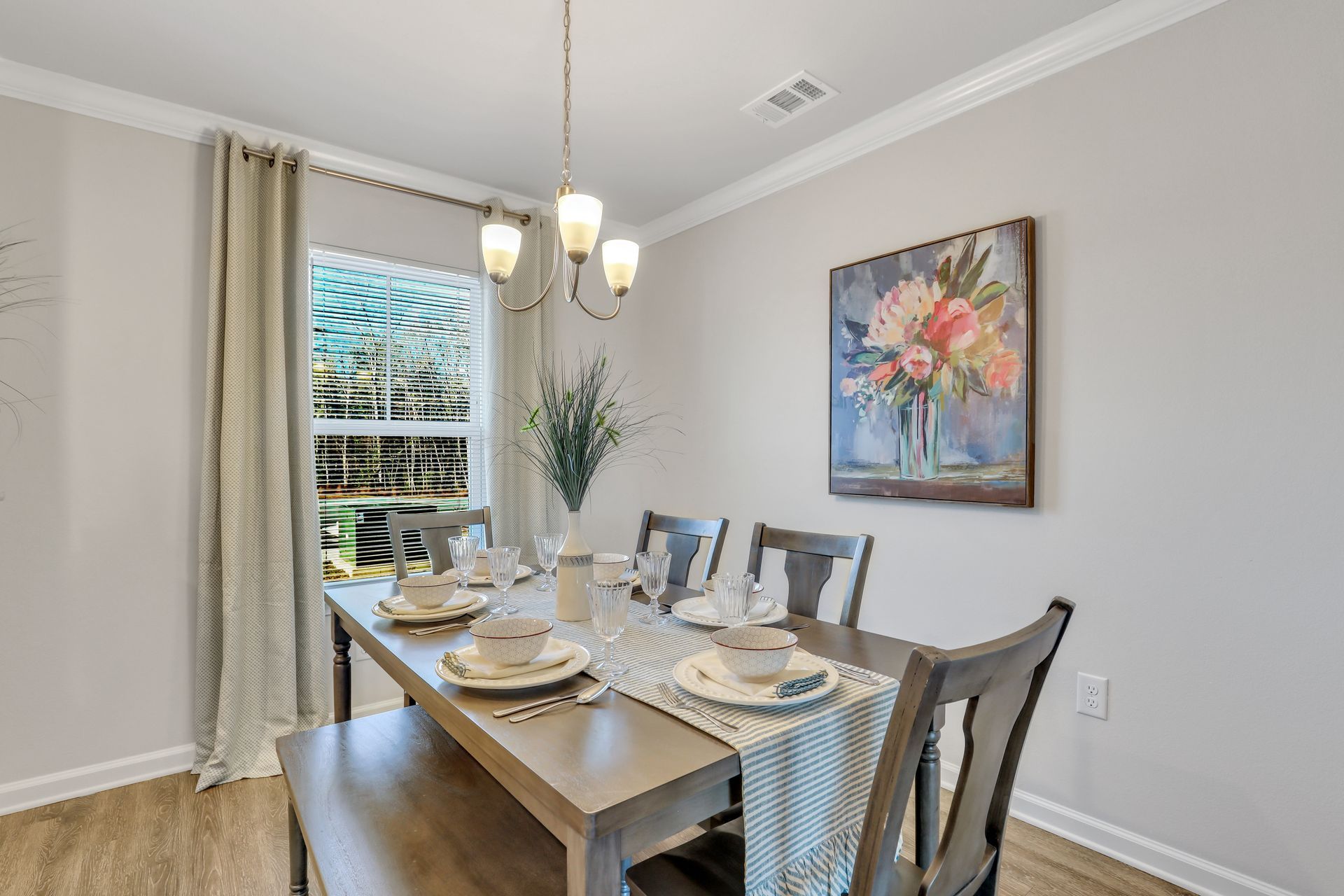 A dining room with a table and chairs and a painting on the wall.