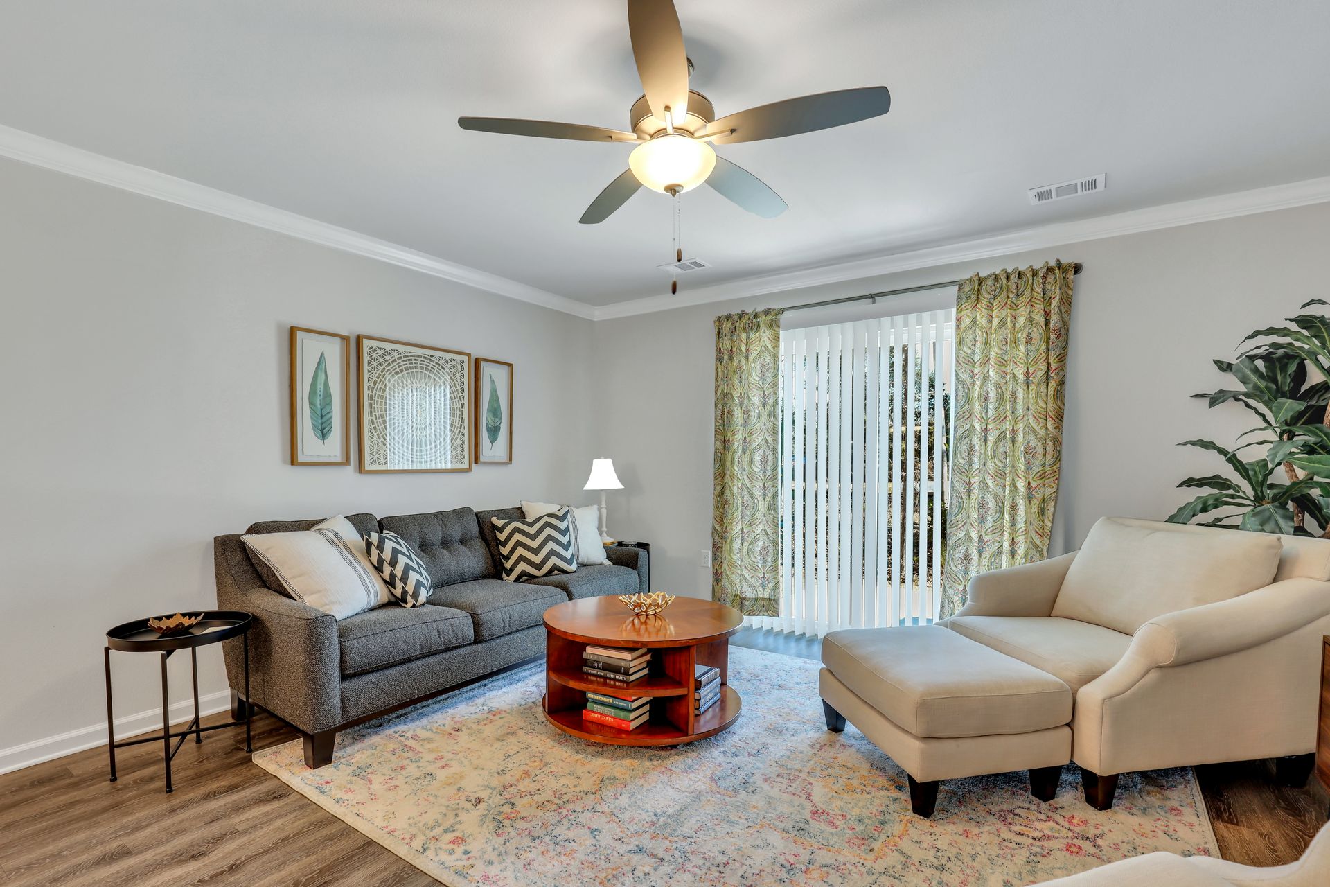 A living room with a couch , chair , coffee table and ceiling fan.
