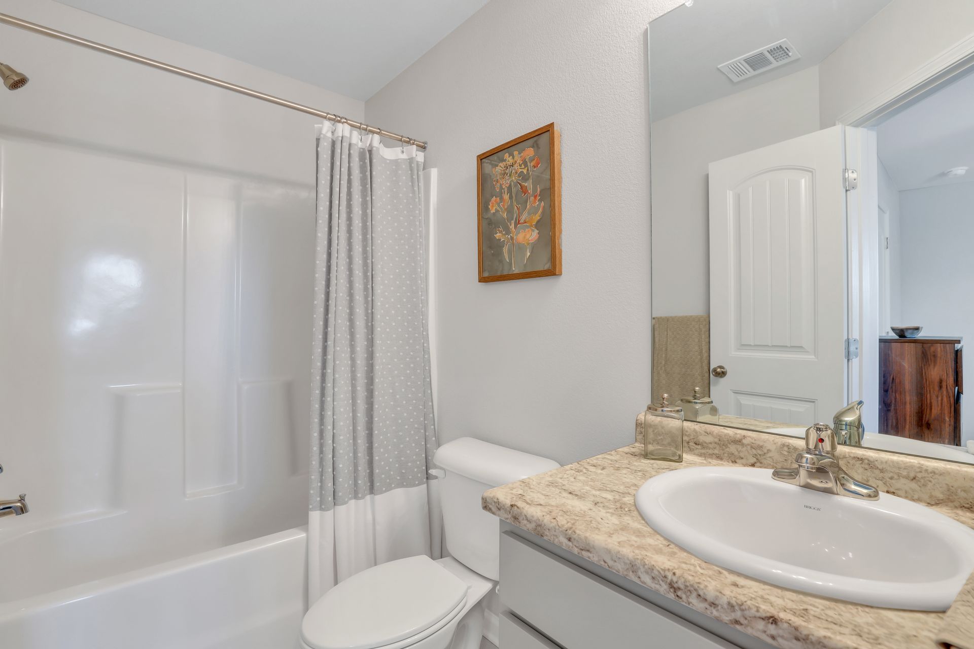 A bathroom with a toilet , sink , bathtub and mirror.