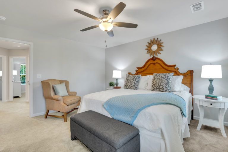 A bedroom with a large bed and a ceiling fan