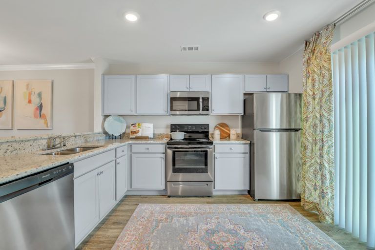 A kitchen with stainless steel appliances and white cabinets.