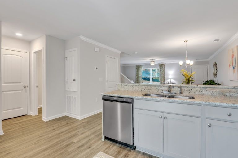 A kitchen with white cabinets and a stainless steel dishwasher.