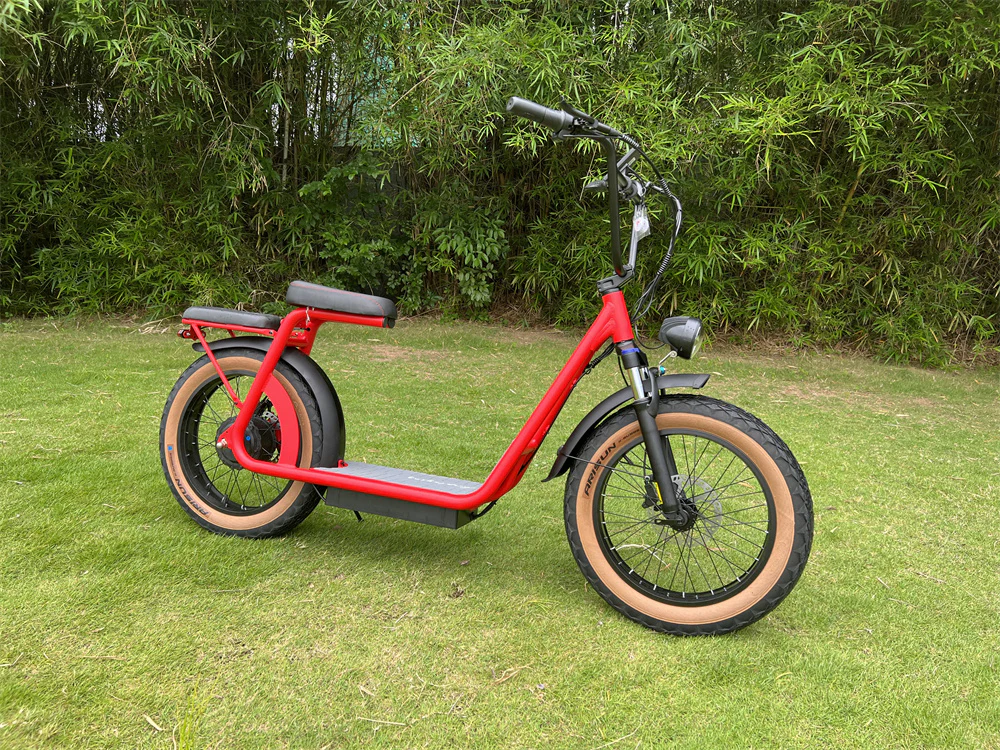 A red beachcomber electric bike is parked on a lush green field.