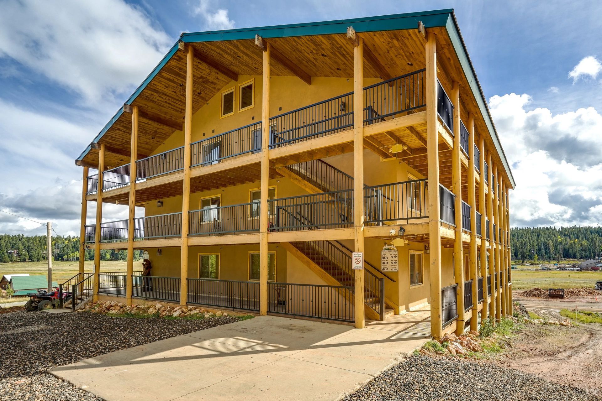 Three-story building with light-colored exterior, balconies, and a ramp. Located in a natural setting.