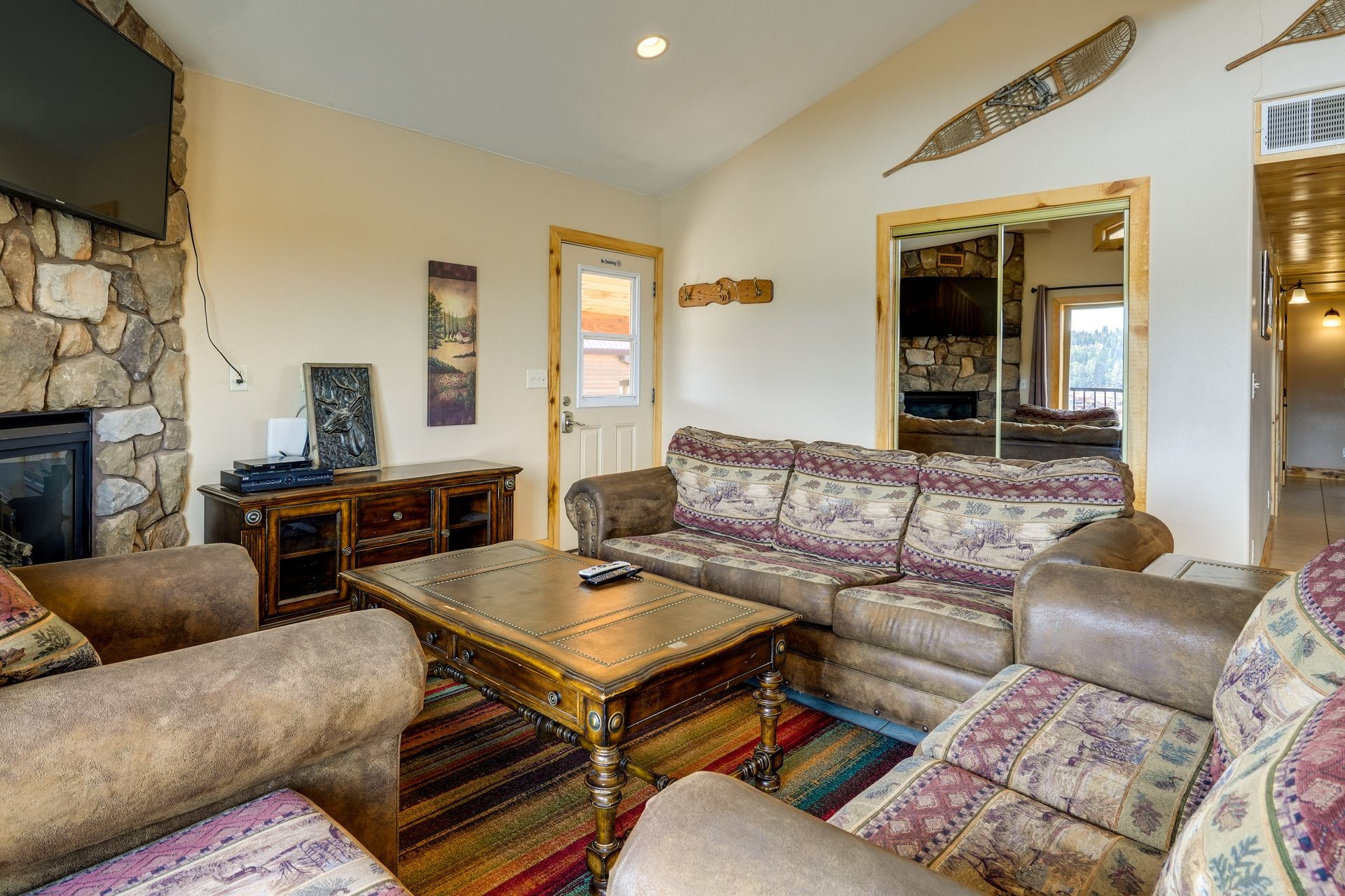 A cozy living room with a stone fireplace, brown leather sofa, and rustic wooden furniture.