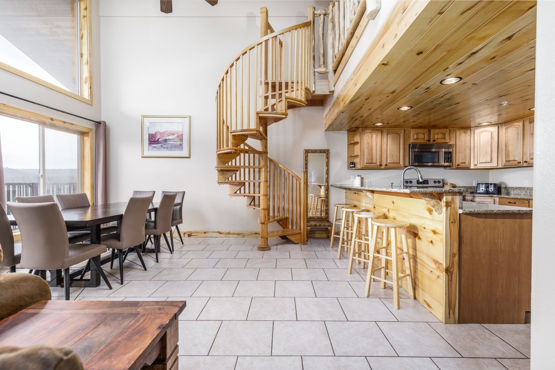 Spacious open-concept living space with a kitchen, dining area, and a wooden spiral staircase.