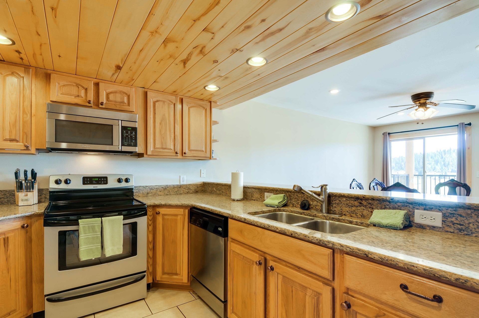 Kitchen with light wood cabinets, granite countertops, and stainless steel appliances.  A pass-through.