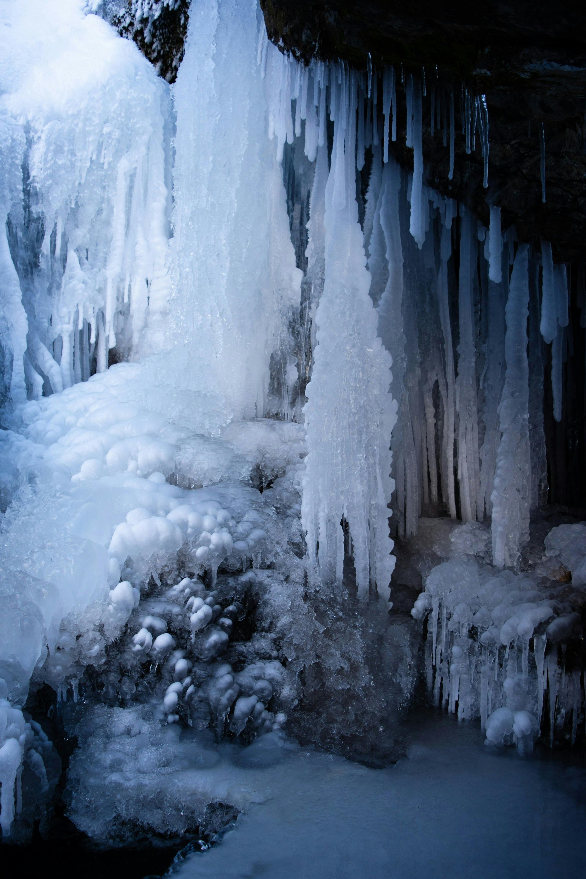 Frozen waterfall with icicles and snow, in shades of white and blue.